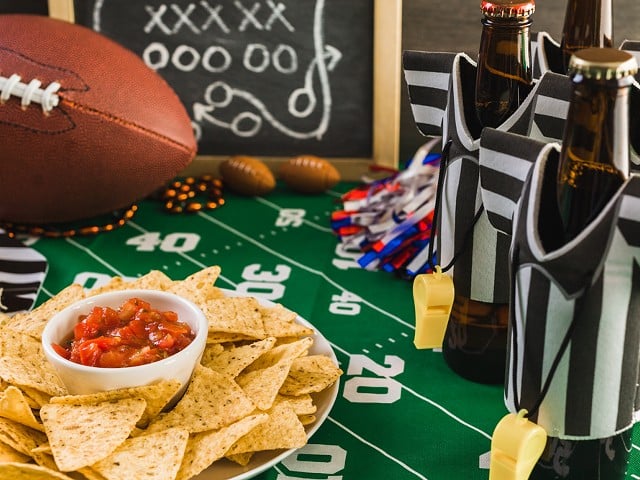 Super Bowl party table with beer, football, chips, and salsa.