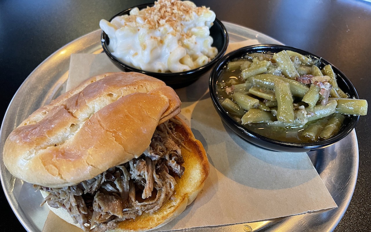 The Smokery's pulled pork is soft and juicy and deeply smoky, falling into thin shreds on a good brioche bun. It's shown with sides of Gouda mac and long-simmered green beans.