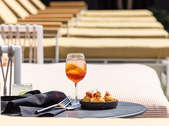 Paseo/Myriad Hotel Swim Club
Primavera Spritz


Enjoy poolside sips from Paseo with a day pass to Myriad Swim Club. Open Tuesday-Sunday, locals can snag a spot by the pool for just $10 each weekday. Enjoy the Primavera Spritz, a modern, seasonal take on a classic Mediterranean Aperol Spritz. Black tea infuses the Aperol with a smoky, earthy aroma while a house-made peach shrub adds a light, sweet touch.
