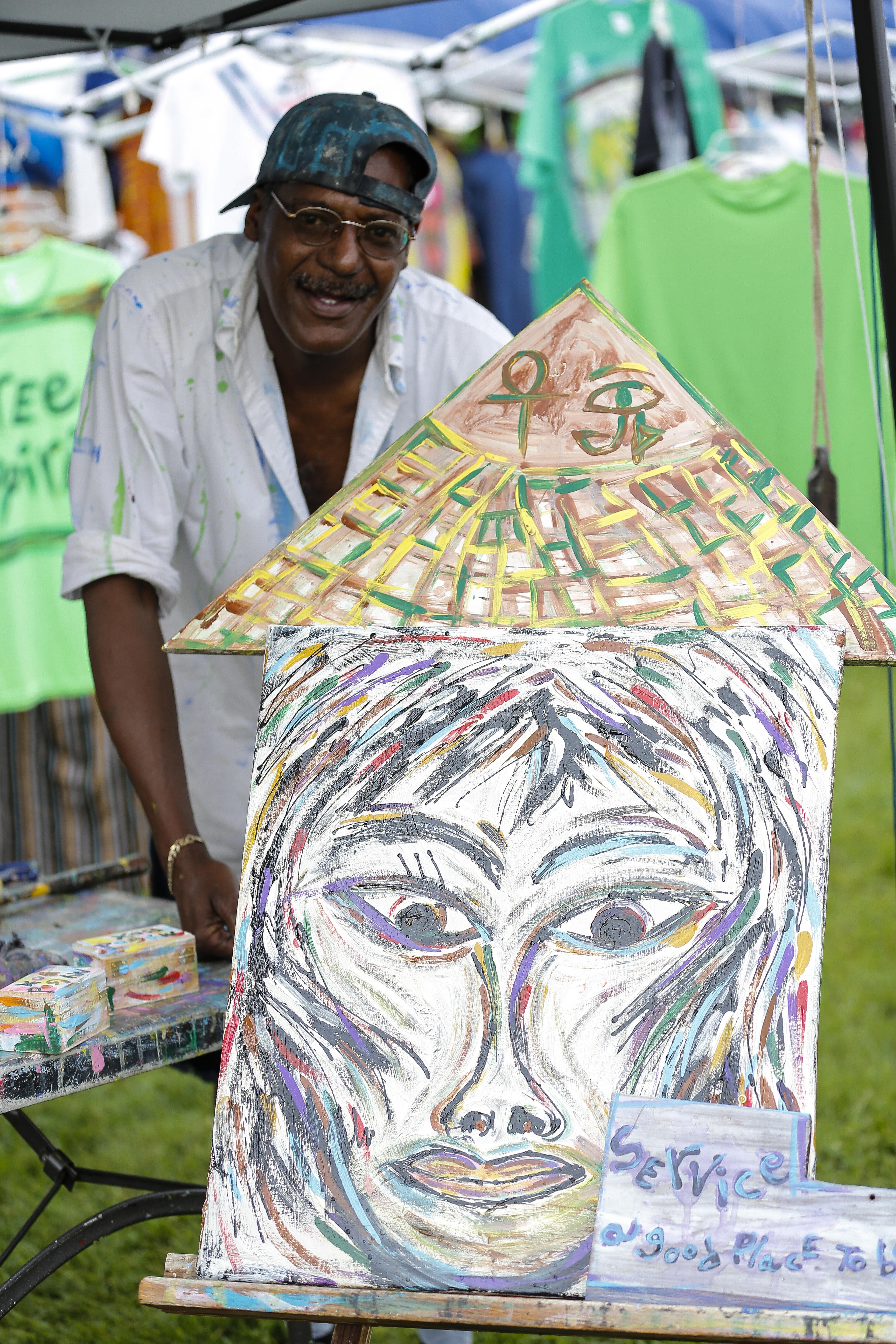 Daniel Horton stands beside one of his pieces in his tent at the Kentucky Reggea Festival. Horton owns Songs For Seba at 1124 Bardstown Road in the Highlands.