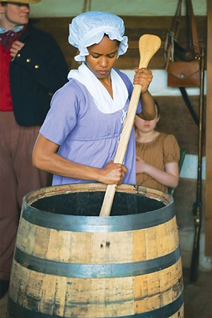 Sidney Edwards stirs mash in a barrel. - Heather R. Hiner  StoryMoon Phtg