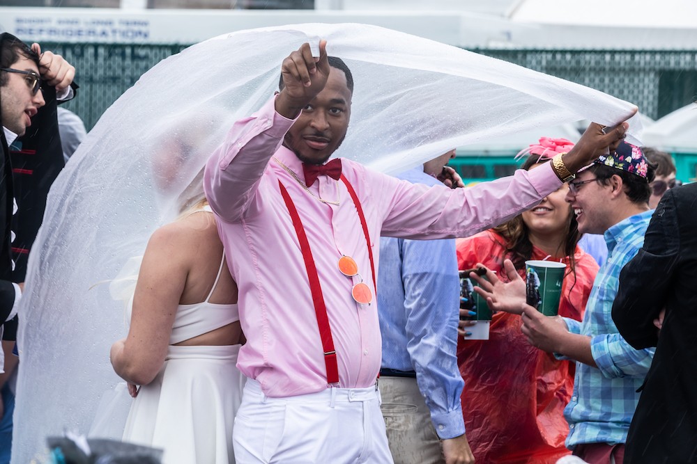 Derby goers shield themselves from the rain with ponchos and sheets of plastic. - KATHRYN HARRINGTON