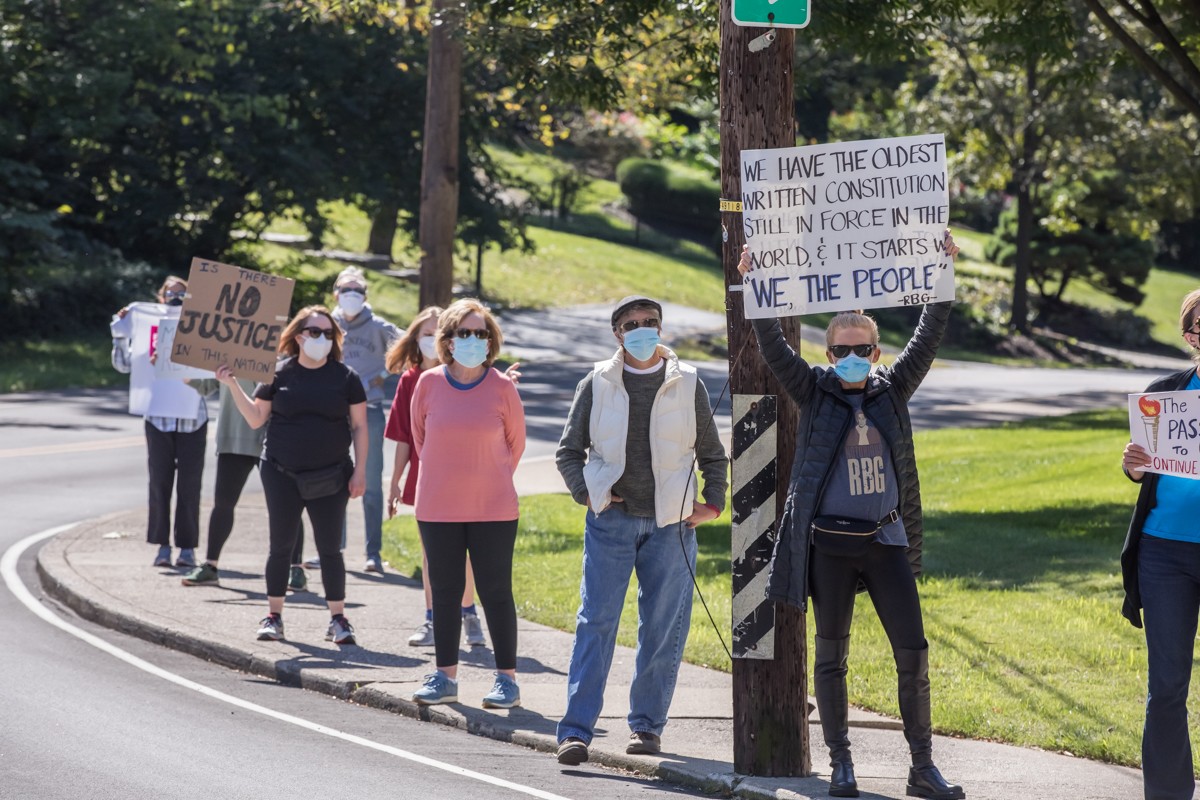 Protesters held up signs honoring the late Supreme Court Justice Ruth Bader Ginsburg outside the home of Senator Mitch McConnell on Saturday. - KATHRYN HARRINGTON