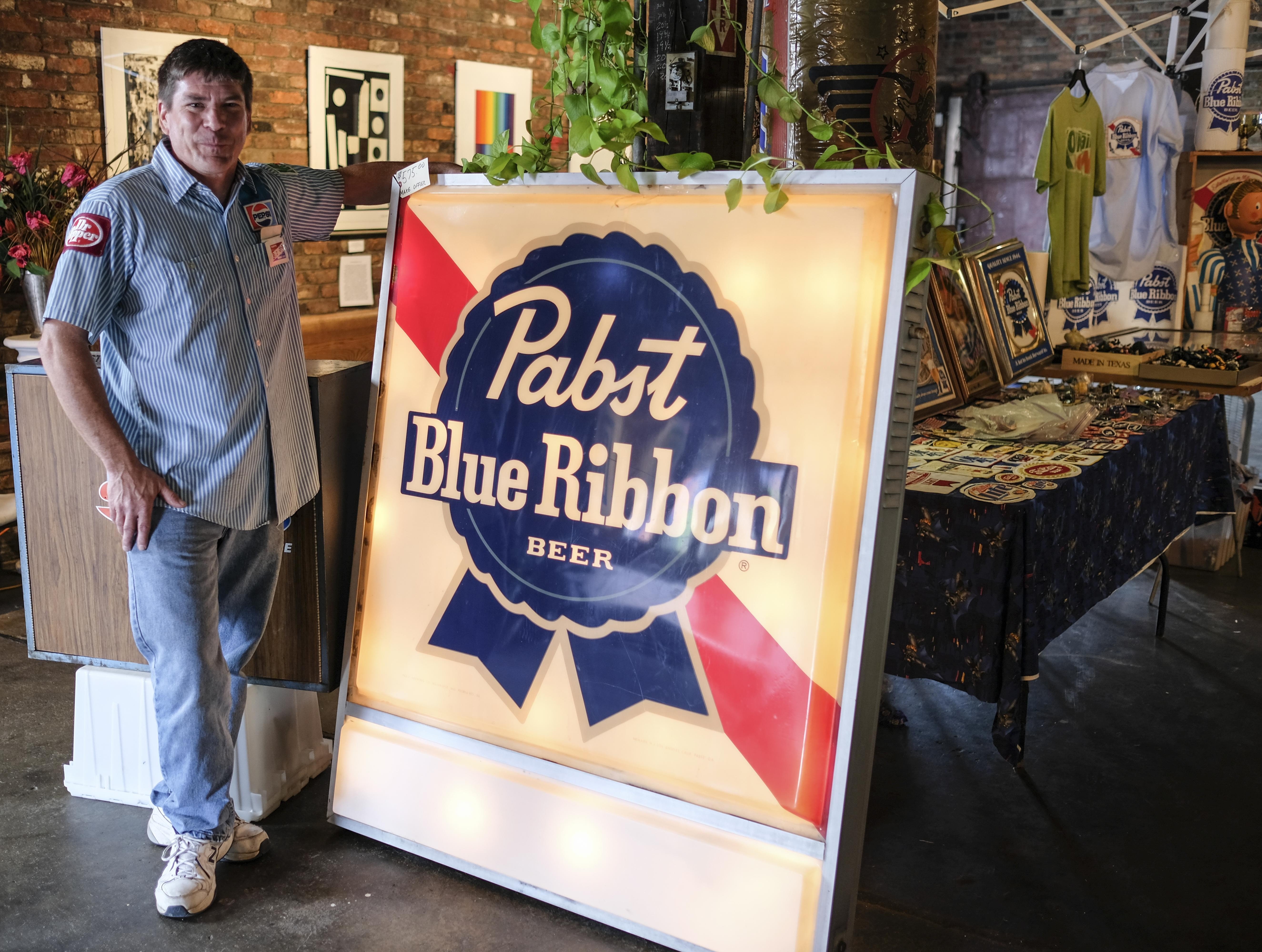 Derrin Pickett of Evansville, Indiana poses beside his large Pabst Blue Ribbon Beer sign next to his display tables at the Beatersville Car and Bike Show.  Pickett says that he sets up about four or five times a year at different car shows with his beer and car memorabilia. &#147;I kinda dig on it. I used to be all toys, like the hot-wheels, action figures and stuff.  I did this show back in 09&#146; and the guy next to me was selling all of this cool beer stuff. I see that stuff all the time at garage sales and good will, and I just didn't know there was a market for it.  But it&#146;s this young hipster crowd.&#148;
