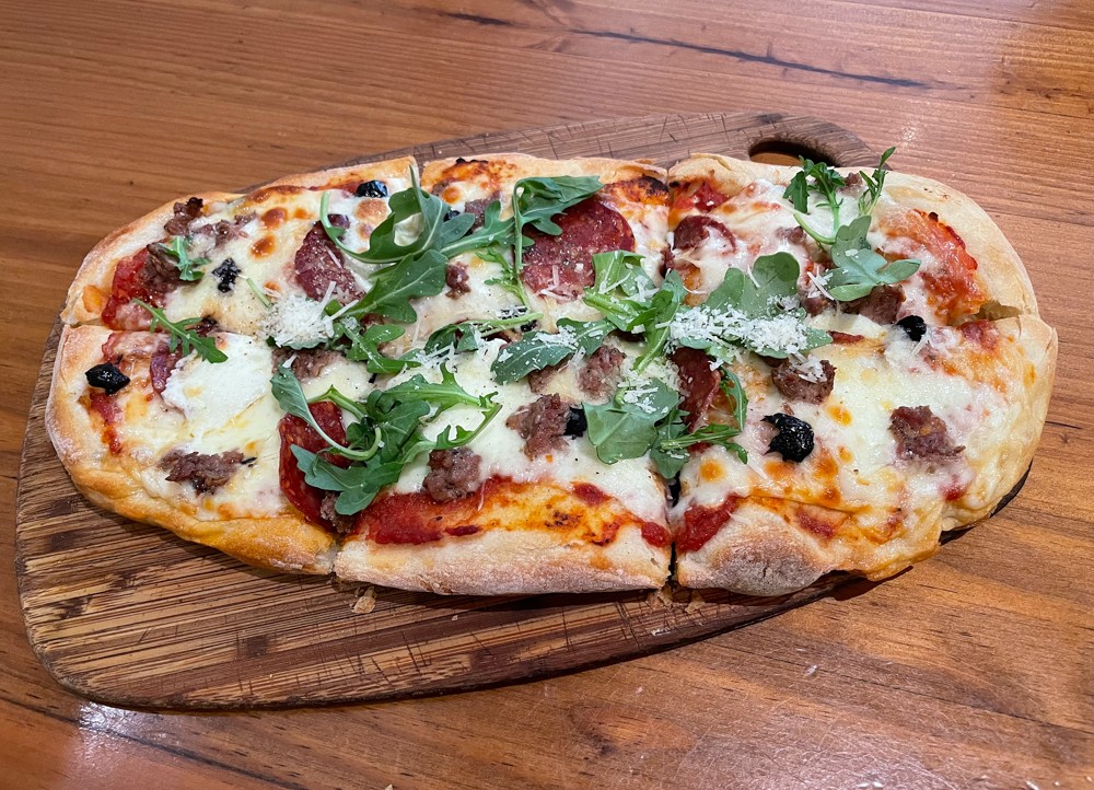 Is it a pizza? Well, not exactly. I felt a need to explain in my review how Blue Dog Bakery's hand-formed flatbread dressed with tomato sauce, cheese, and Red Hog sausage and pepperoni fills a pizza-size space, in a good way.