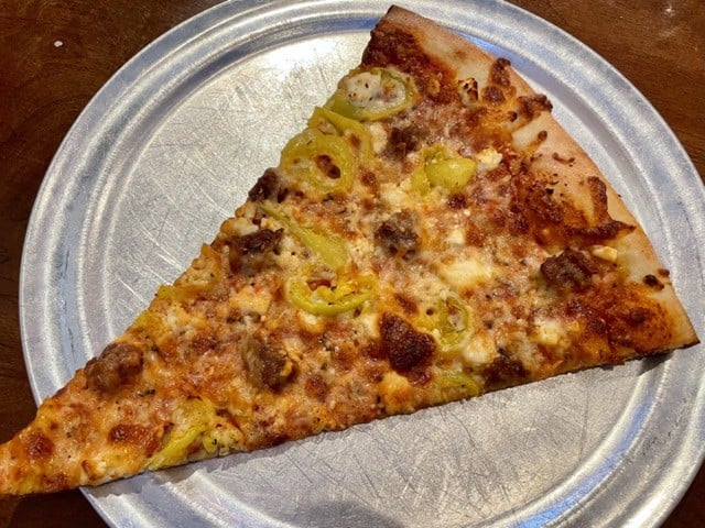 The Post is famous for its oversize, New York City style pizza by the slice, which changes daily. Spicy sausage, banana peppers, and feta cheese did well by this tasty slab. - Garr