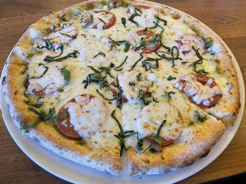 A margherita flatbread pizza features the traditional mix of basil, tomato, and mozzarella plus a schmear of pesto and a generous hand with the molten cheese.